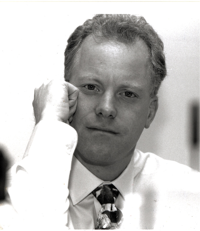 Portrait of Peter Slom wearing a light-colored shirt and patterned tie.