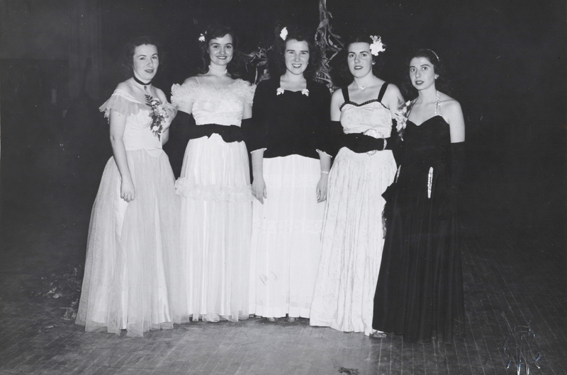 Five women wearing ball gowns pose for a photo.