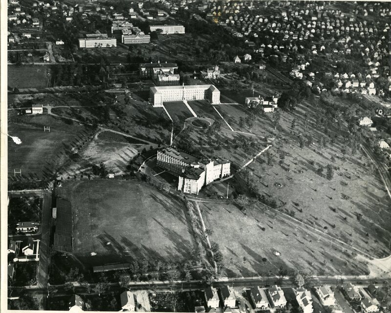 Providence College campus circa 1939, featuring multiple buildings, open fields, and a circular driveway, set within a suburban neighborhood.