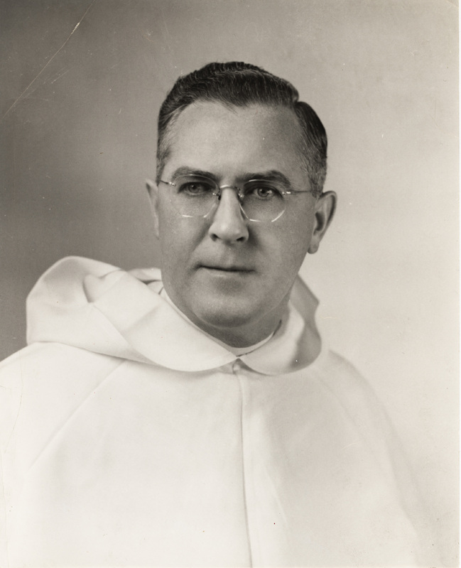 Portrait of Robert Slavin wearing glasses and a white habit with a hood, posed against a plain light background.