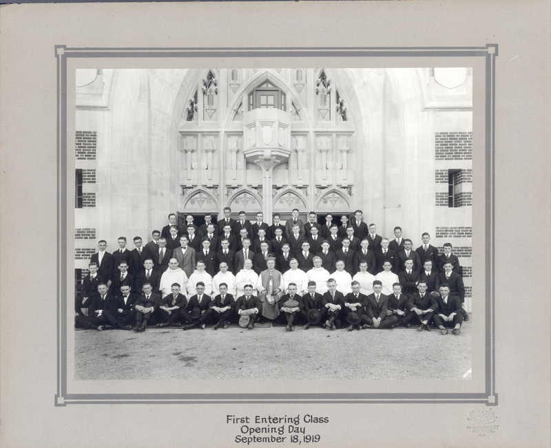 The first entering class on Opening Day, September 18, 1919, posed in front of a Gothic-style building entrance, with individuals dressed formally in suits and ties.