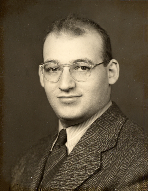 Portrait of Samuel Katznelson wearing glasses, a suit jacket, collared shirt, and tie.