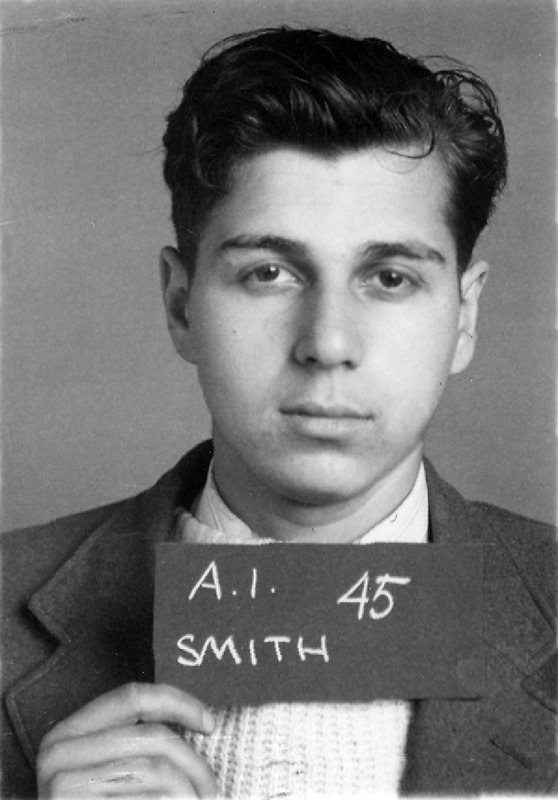 Portrait of Abraham Smith wearing a suit and holding a sign that reads 'A.I. 45 SMITH,' with a plain background.