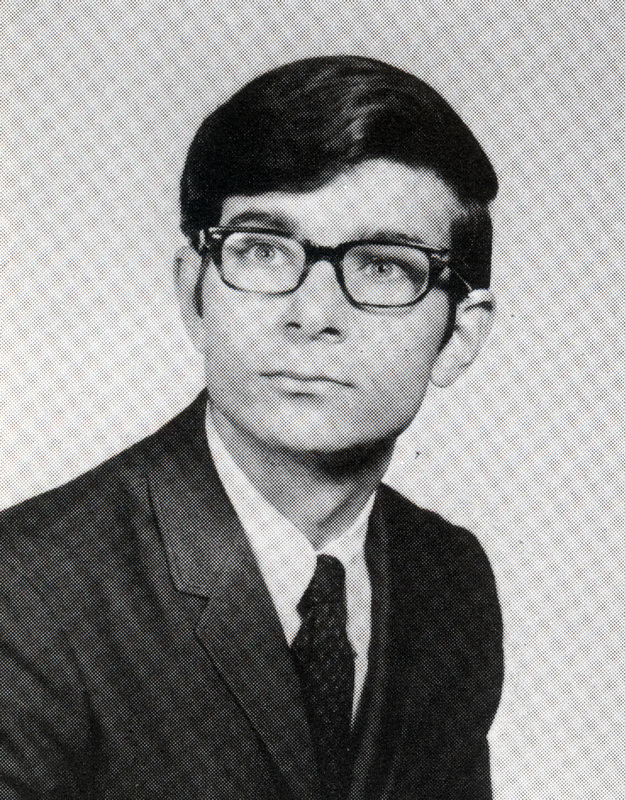 Portrait of Austin Sarat wearing a suit and tie in front of a light background.