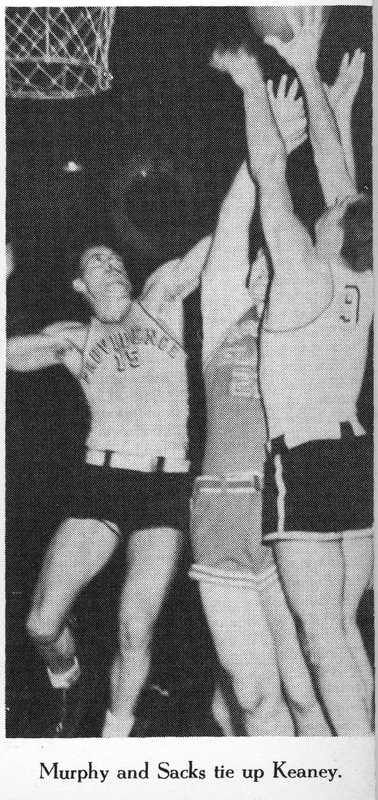 A basketball game with three players jumping near the basket, including one in a 'Providence' jersey with number 15 and another in jersey number 9.