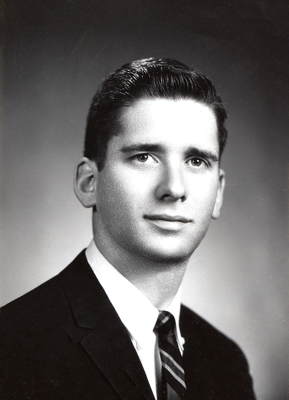 Portrait of Edward Feldstein wearing a suit and tie in front of a light background.