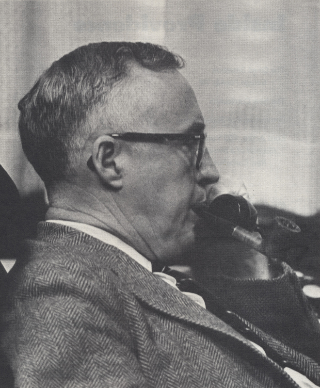 Rev. Paul van K. Thomson smoking from a pipe and wearing a suit.