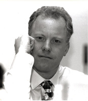 Portrait of Peter Slom wearing a light-colored shirt and patterned tie.