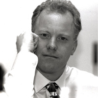 Portrait of Peter Slom wearing a light-colored shirt and patterned tie.