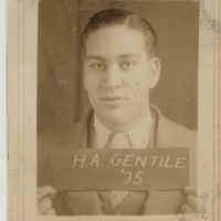 Portrait of Herman Gentile in a suit and tie holding a sign that reads 'H.A. GENTILE '35.'
