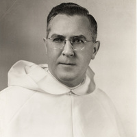 Portrait of Robert Slavin wearing glasses and a white habit with a hood, posed against a plain light background.