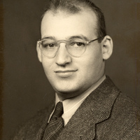 Portrait of Samuel Katznelson wearing glasses, a suit jacket, collared shirt, and tie.