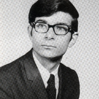 Portrait of Austin Sarat wearing a suit and tie in front of a light background.