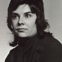 Portrait of Fay Saber wearing black clothes in front of a light background.
