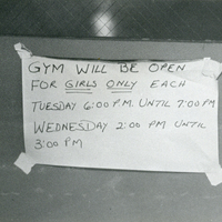 A piece of paper taped to a door that reads 'Gym will be open for girls only each Tuesday 6:00pm until 7:00pm Wednesday 2:00pm until 3:00pm.'